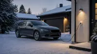 Bil med motorvärmarkabel ansluten på en snöig uppfart